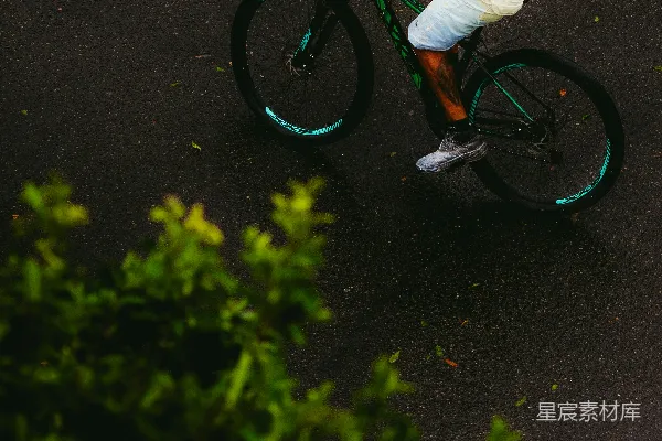 高清摄影 穿黄衬衫的男人在湿路上骑自行车。