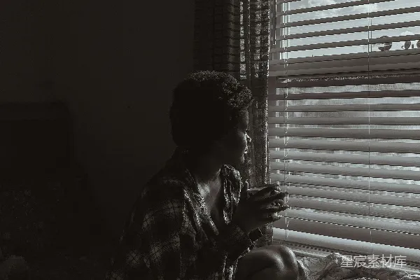 高清摄影 一个女人坐在床上看着她的手机。