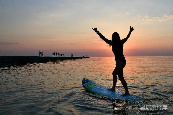 高清摄影 夕阳下，一个女人的轮廓在冲浪板上。