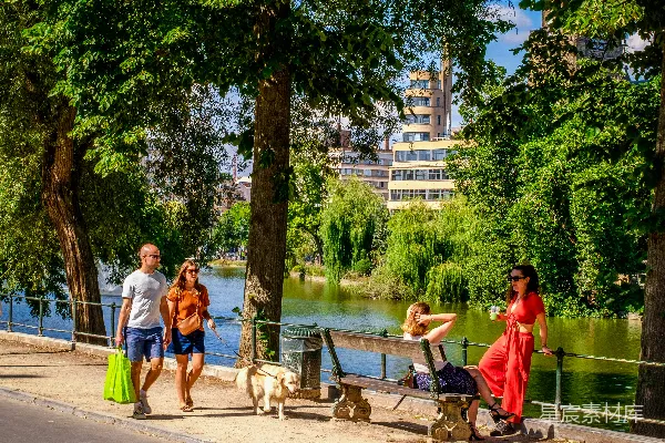 高清摄影 人们在湖边遛狗，背景是建筑物。