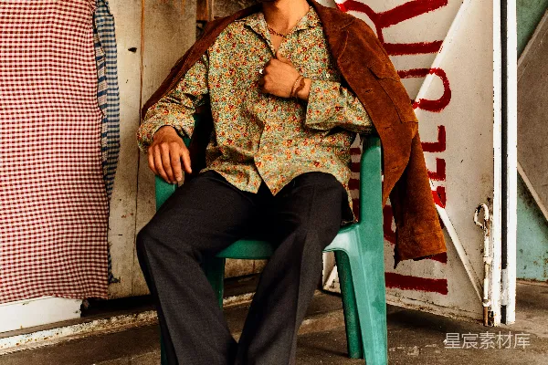 高清摄影 一个男子坐在一把绿色的椅子上，旁边有一块滑板。