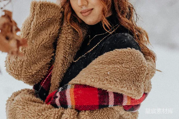 高清摄影 一个女人站在雪中，双臂抱头。