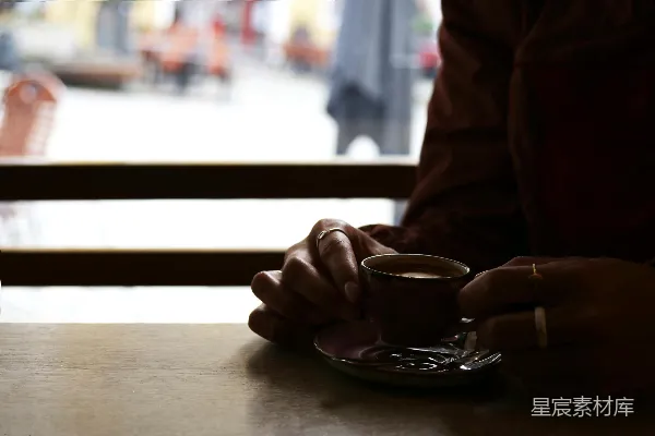 高清摄影 坐在桌子旁的人手中拿着一杯咖啡。