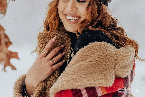 高清摄影 一个女人站在雪中，穿着夹克和帽子。