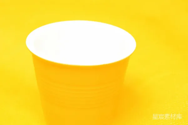 高清摄影 黄色塑料杯放在橙色表面上