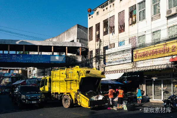 高清摄影 一辆黄色的垃圾 truck 停在了一栋建筑前面。