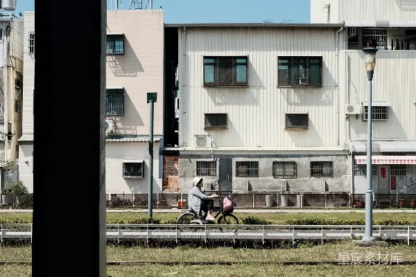 高清摄影 人们骑车经过建筑和铁轨。