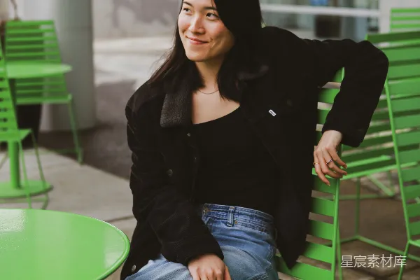 高清摄影 一个女人坐在一把绿色长凳的顶端。
