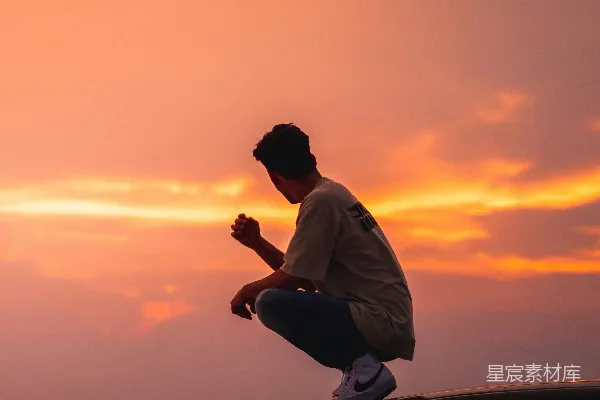 高清摄影 白长袖衬衫男子穿着黑色长裤坐在一辆车的引擎盖上，夕阳西下时。