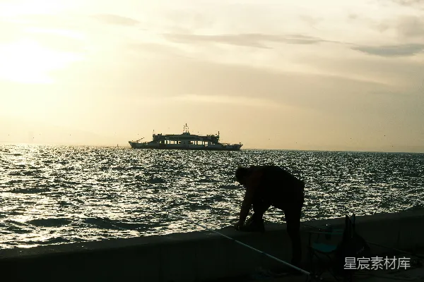 高清摄影 海边一个人的侧影正在钓鱼，背景中有渡轮。