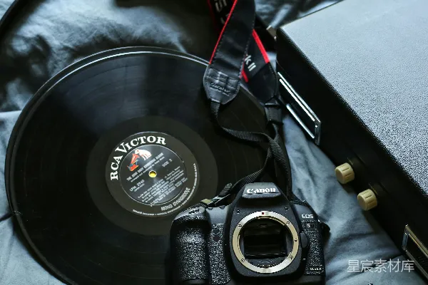 高清摄影 黑色的佳能EOS 5D DSLR相机旁边有一个黑色的 RCA Victor 胶片唱片。