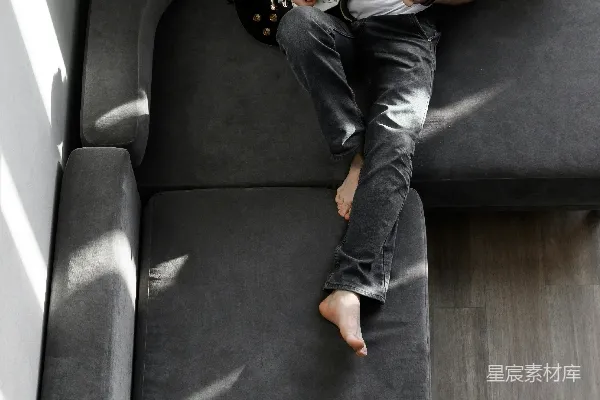 高清摄影 一个男人坐在沙发上弹吉他。