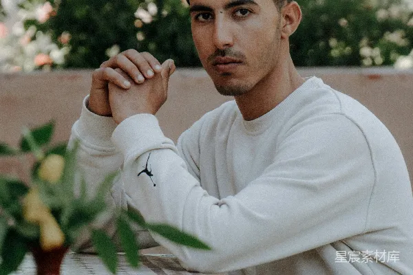 高清摄影 一个男子坐在一张桌子旁，桌子上有盆鲜花。