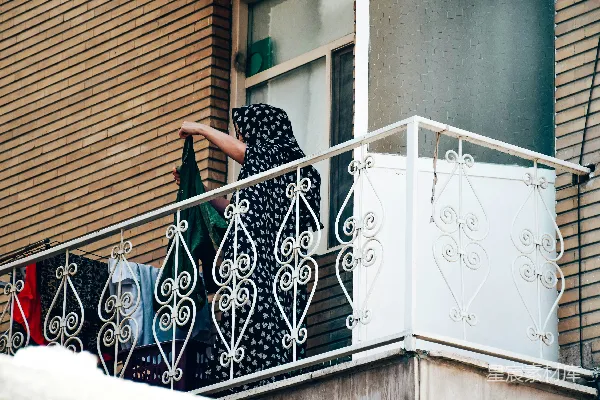 高清摄影 一个女人站在一栋建筑旁边的一个阳台上