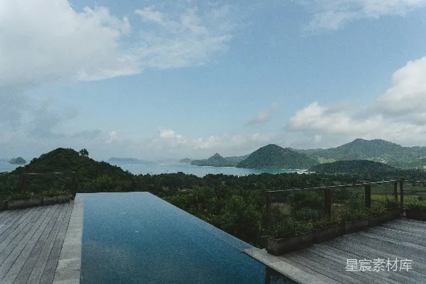 高清摄影 一个有阳台和树的泳池，背景是山。