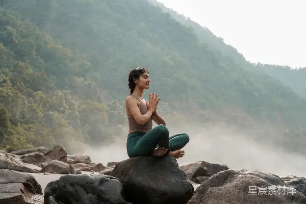 高清摄影 一个女人坐在一块岩石上，旁边是条河。