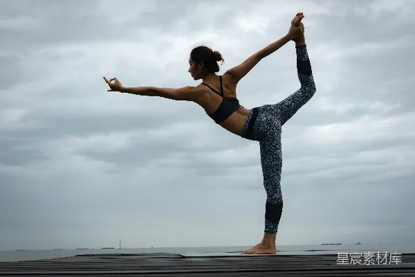 高清摄影 黑色紧身胸衣和蓝色运动 leggings 的女性在白天进行瑜伽练习。