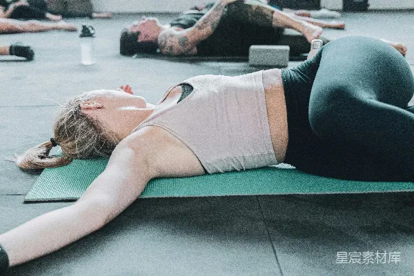 高清摄影 白色文胸穿着的女子躺在绿色瑜伽垫上，穿着黑色短裤。