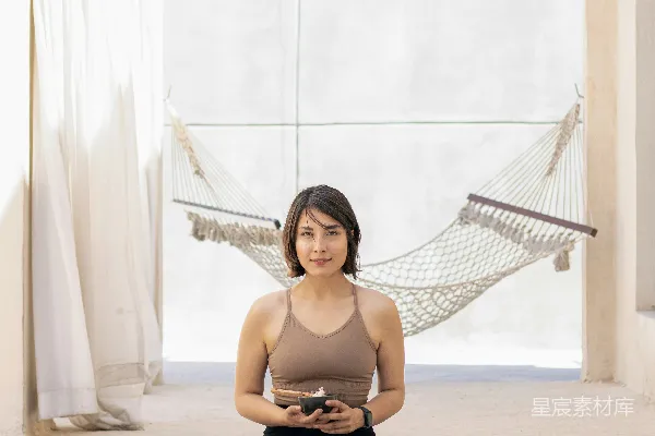 高清摄影 一个女人坐在吊床里的瑜伽垫上
