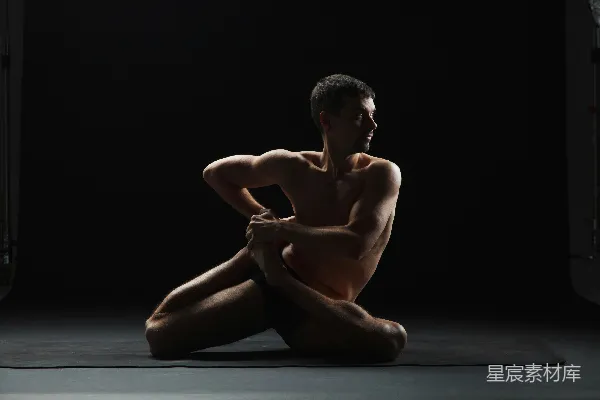 高清摄影 一个裸体的男人坐在一张垫子上，处在黑暗中。