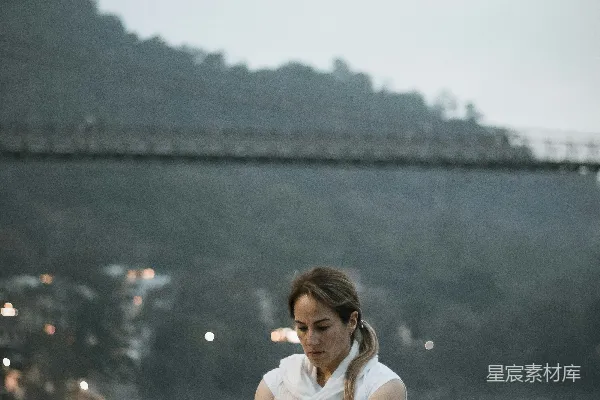 高清摄影 地上坐着一位妇女，面前是一条河。