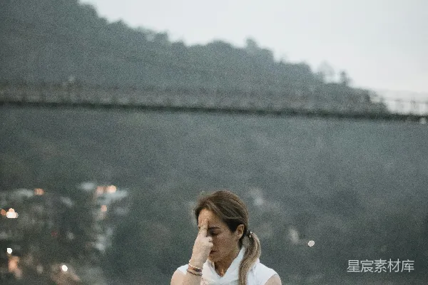 高清摄影 地上坐着一位妇女，面前是一条河。