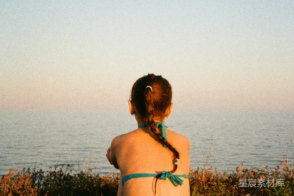 高清摄影 一个女人坐在一块绿色垫子上，旁边是大海。