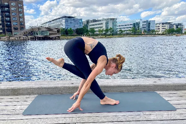 高清摄影 蓝色上衣和蓝色 leggings 的女人在白天靠近水体进行瑜伽练习。