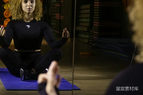 高清摄影 一个女人在一面镜子前坐在垫子上打坐。