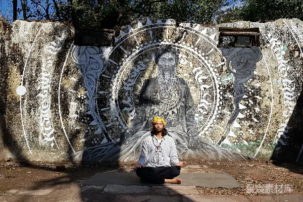 高清摄影 一个男人坐在瑜伽垫前，面前是一幅壁画。