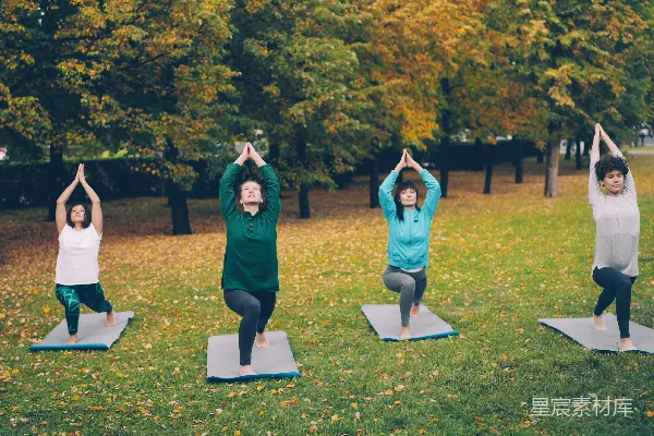 高清摄影 四个妇女在秋日公园练习瑜伽。