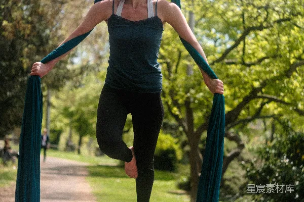 高清摄影 黑色连帽衫和黑色 leggings 的女子在蓝白相间的蹦床上做瑜伽。