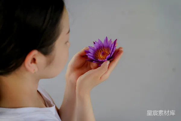 高清摄影 一个女人手里拿着一朵紫色的花。
