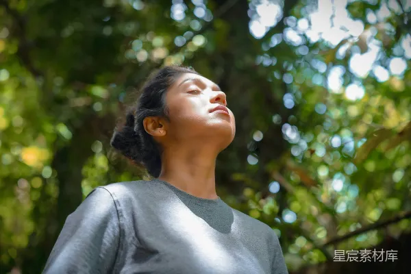 高清摄影 一个女子站在一棵树前，眼睛闭着