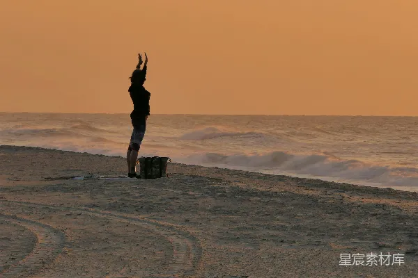 高清摄影 海滩上一个人举着手臂站在那里