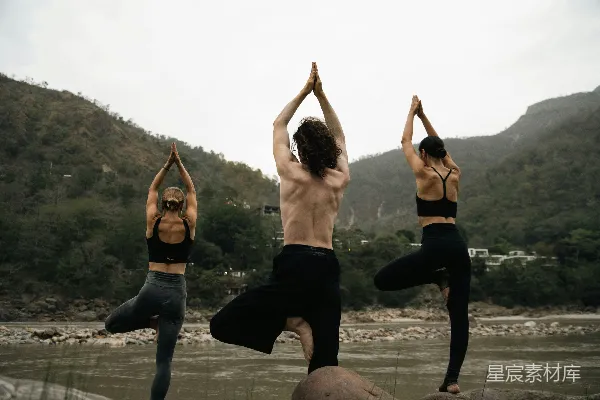 高清摄影 三人在河边一块岩石上做瑜伽