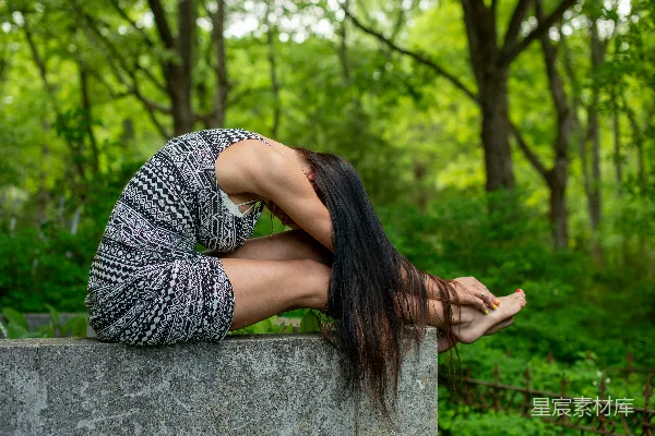 高清摄影 女人在户外的水泥阶梯上穿着连衣裙伸展身体。
