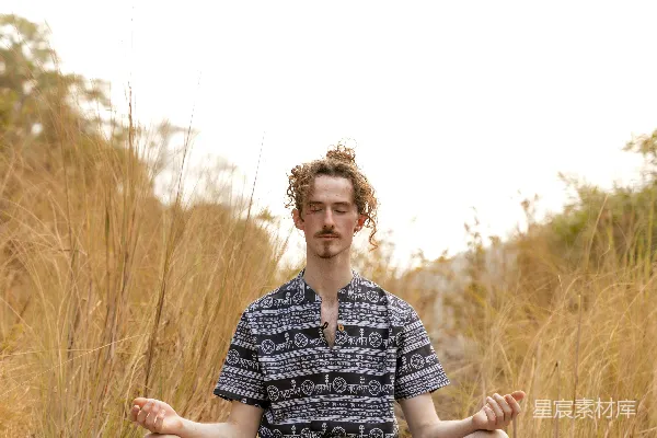 高清摄影 一个男人坐在田野中的岩石顶部。