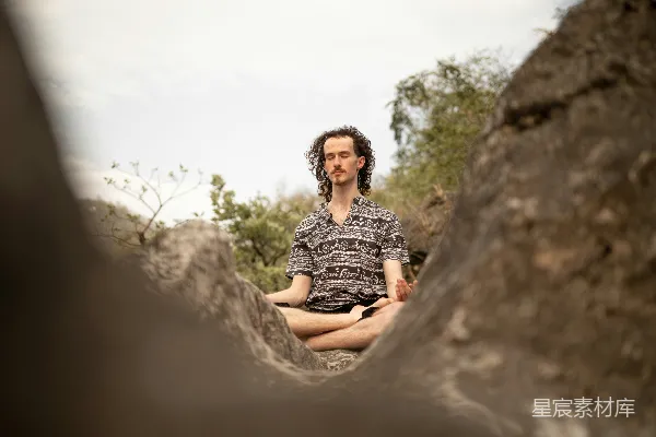 高清摄影 一个男人坐在森林中央的一块岩石上