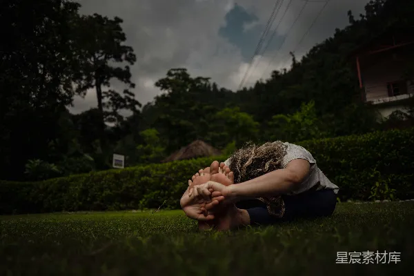 高清摄影 一个女人坐在草地上，用手捂住脸。