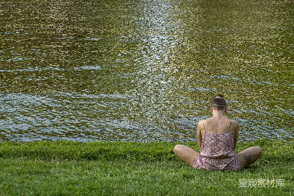 高清摄影 穿着棕色连衣裙的女子坐在绿色草地上，靠近一片水体的白天