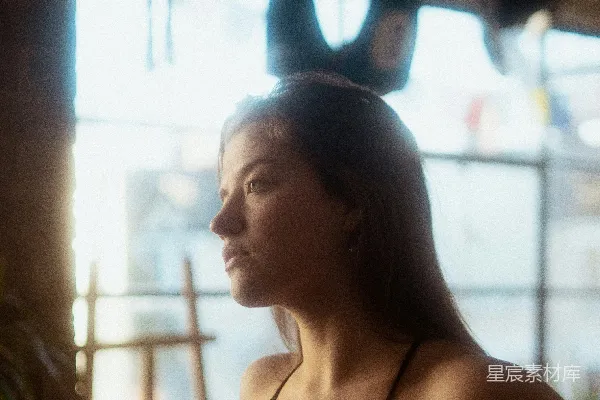高清摄影 一个女人站在窗户前，手里拿着手机。