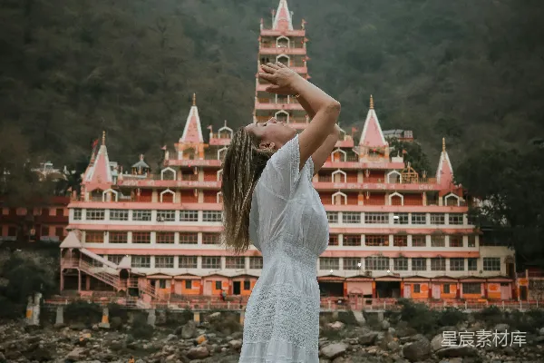 高清摄影 一个穿着白裙子的女人站在一座大建筑物前