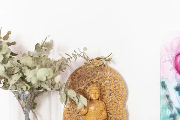 高清摄影 一张桌子上放着一尊佛像，旁边放着一束花。