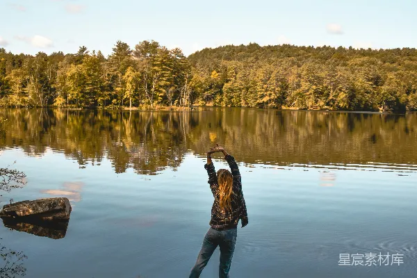 高清摄影 一个女子站在一块岩石附近，靠近一片水域。