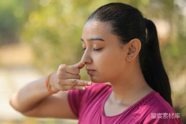 高清摄影 一个年轻女子在户外练习鼻饲 Alternate nostril breathing。