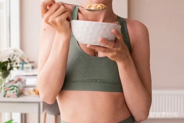 高清摄影 一个穿着运动bra上衣的女人手里拿着一个饭碗