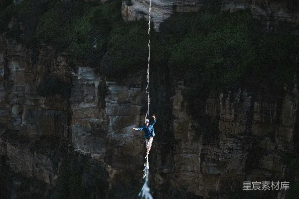 高清摄影 一个男人悬挂在一根绳子上，上方有一片水域。