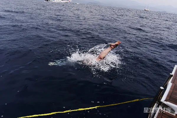高清摄影 海边有人在靠近一艘船的海里游泳。