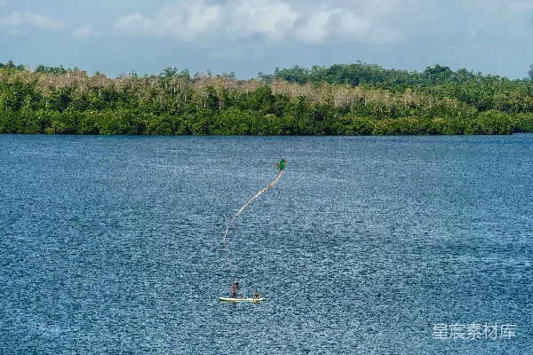 高清摄影 一个人在湖上 parasailing，背景是树木。